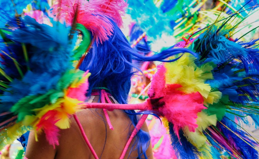 Eine in Regenbogen-Pride-Farben geschmückte Frau von hinten auf einer Faschingsparty